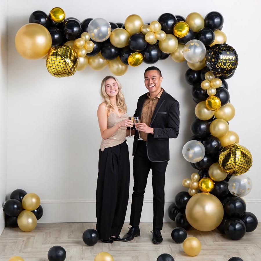 Black, Gold, and Silver Balloon Arch Framing a Toasting Couple — New Years Eve Balloon Garland