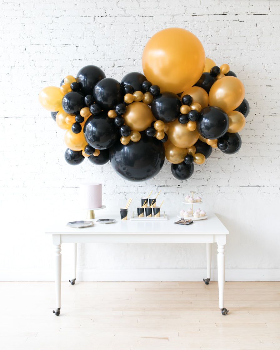 Black and Gold Balloon Garland Above a Party Table — New Years Eve Balloon Garland