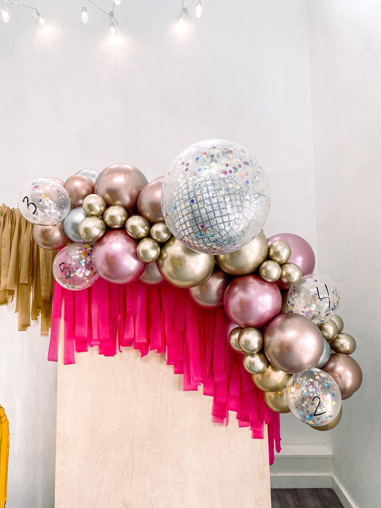 Rose Gold, Gold, Silver Balloon Garland Over a Fringe Backdrop — New Years Eve Balloon Garland